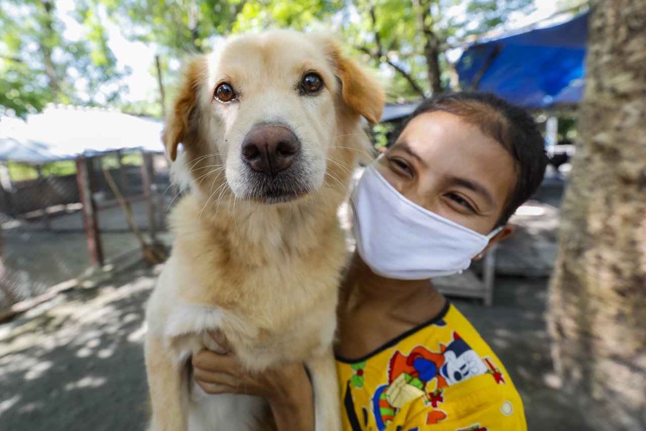 Caretaker at Wat Hua Kho temple in Thailand holding a dog - World Animal Protection
